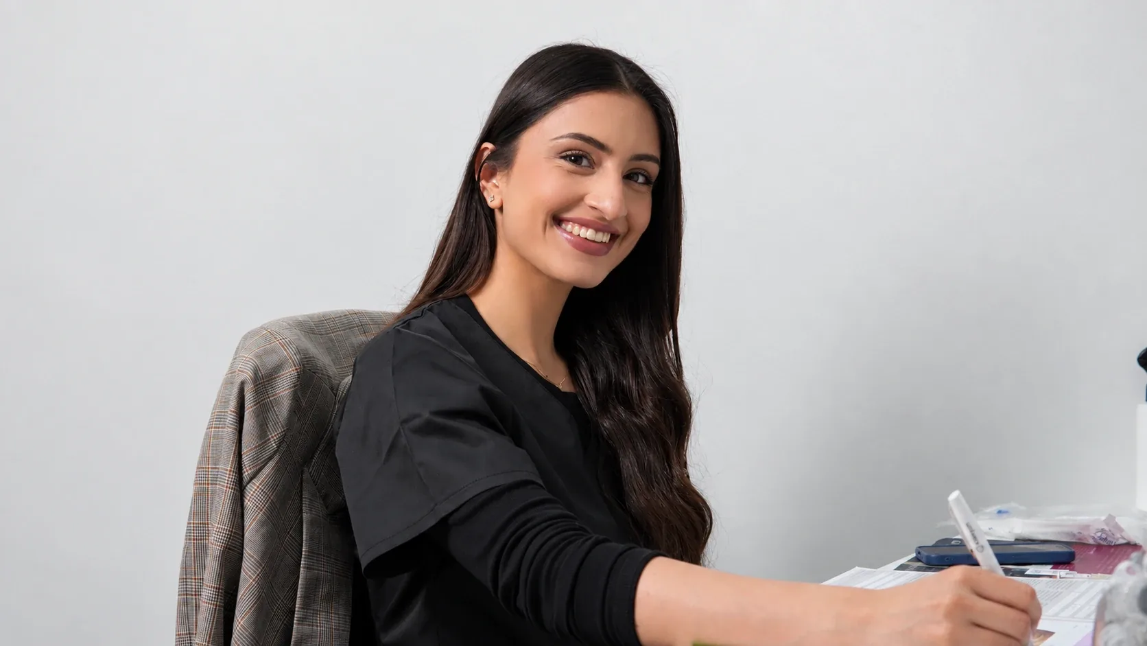 Dr Yasira Joosub smiling at her desk at FY Medical Aesthetics